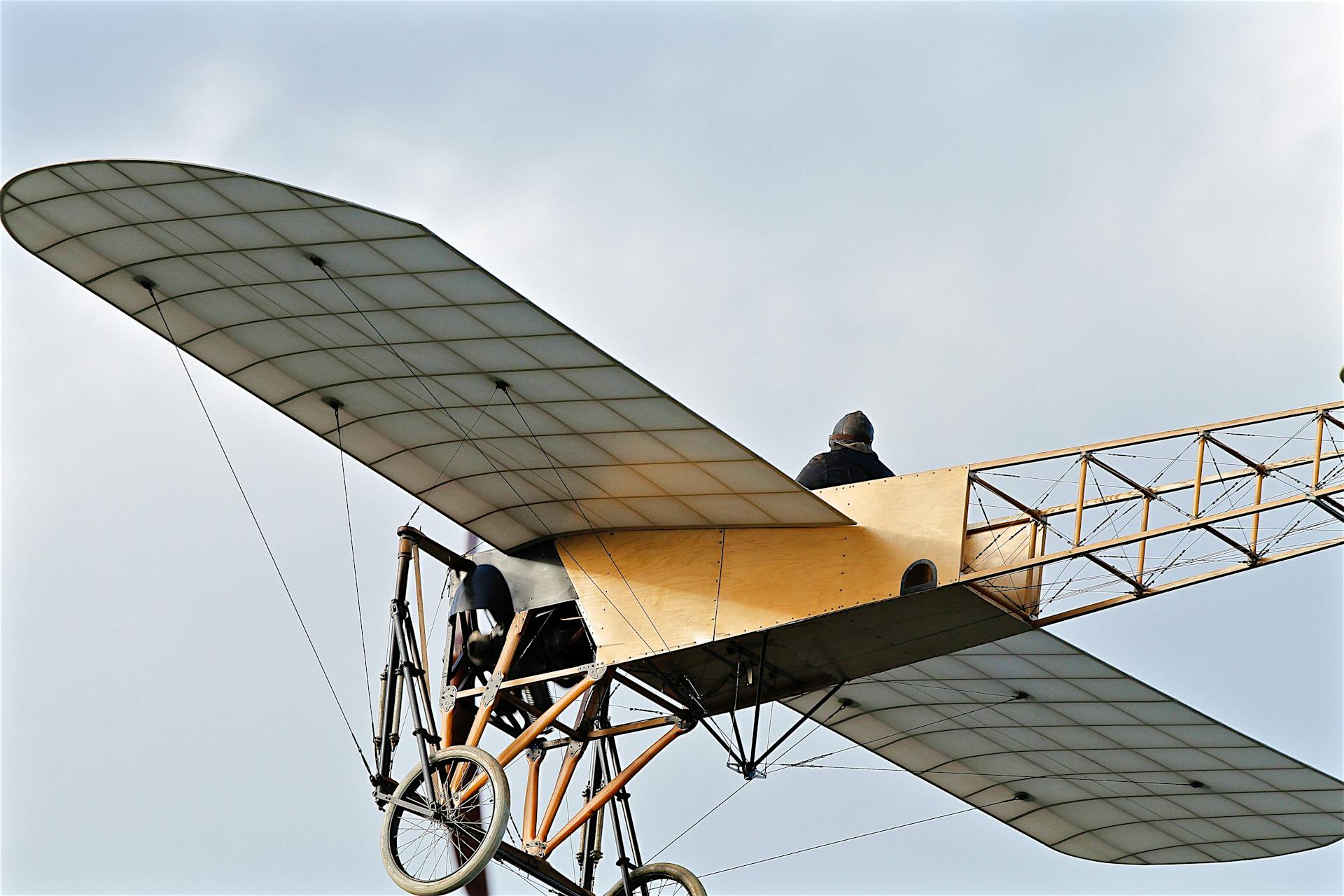 A vintage aircraft in mid-flight with a pilot, depicting classic aviation technology.