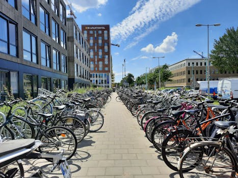 A vibrant urban street filled with parked bicycles under a clear blue sky, showcasing city life.