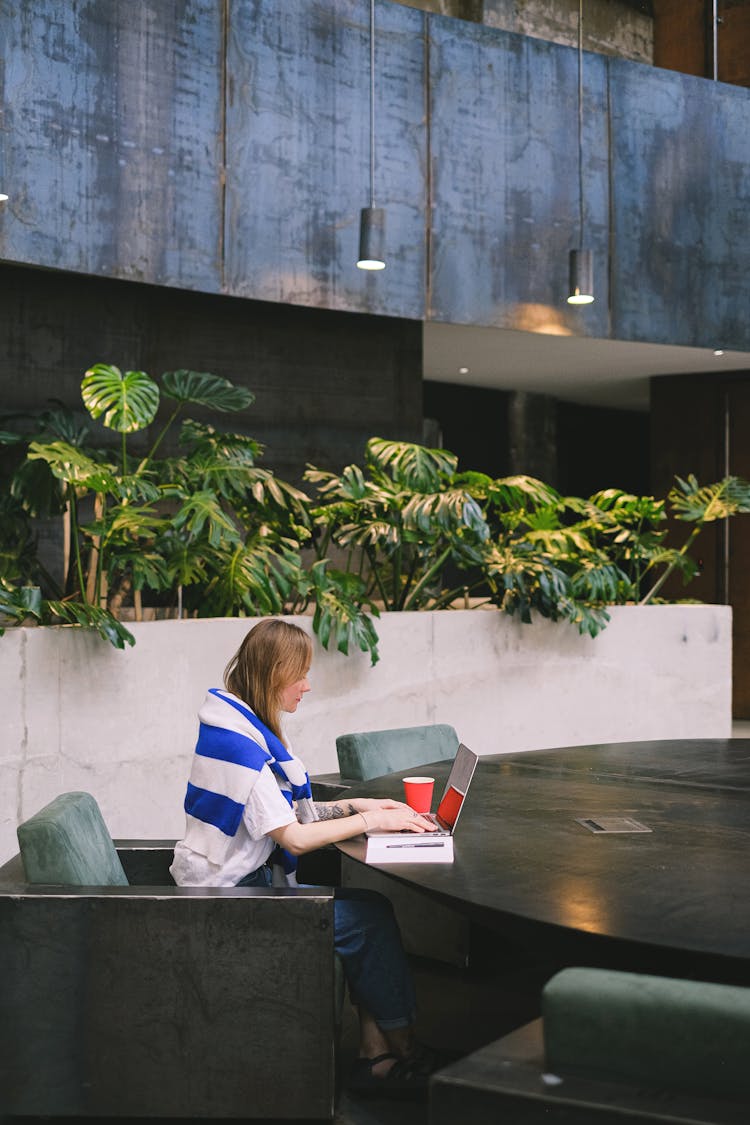 Woman Working On Laptop By Large Black Table On Campus