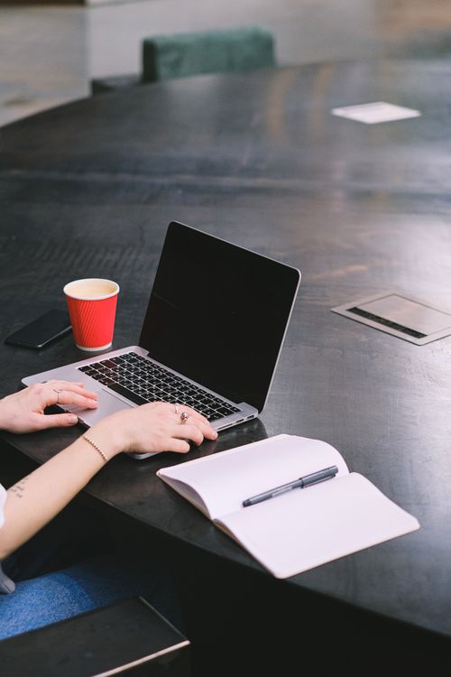 Free Cozy office setup with laptop, notebook, and coffee cup on a large round table. Stock Photo