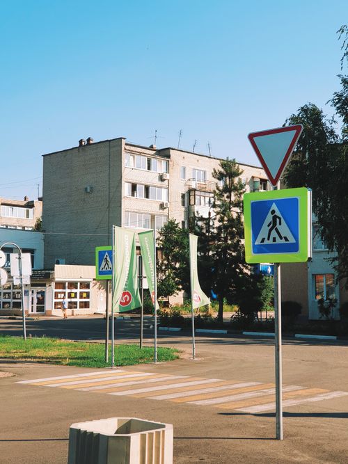 Free An urban intersection with multiple road signs, including pedestrian crossing and yield signs, under clear blue skies. Stock Photo