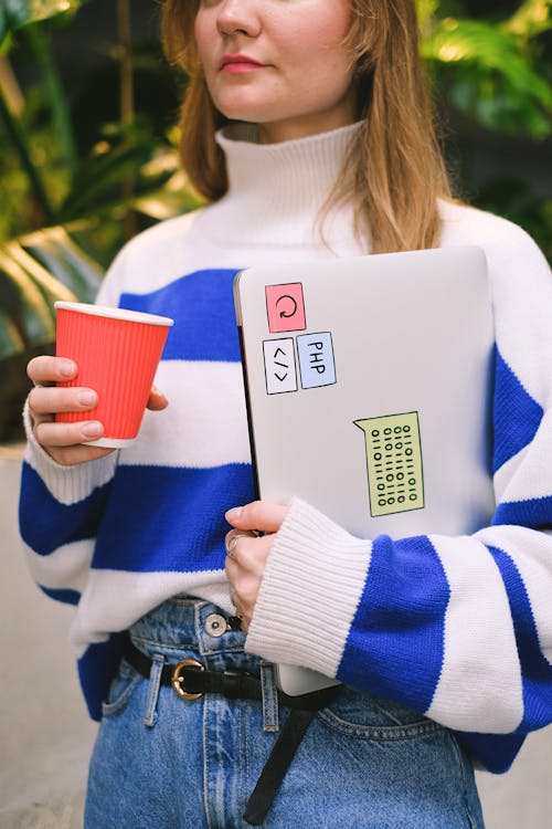 Woman in Striped Sweater Holding Paper Cup and Laptop