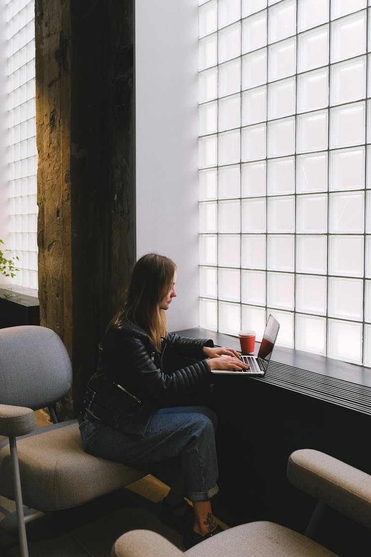 Woman Working On Laptop Sitting By Windowsi