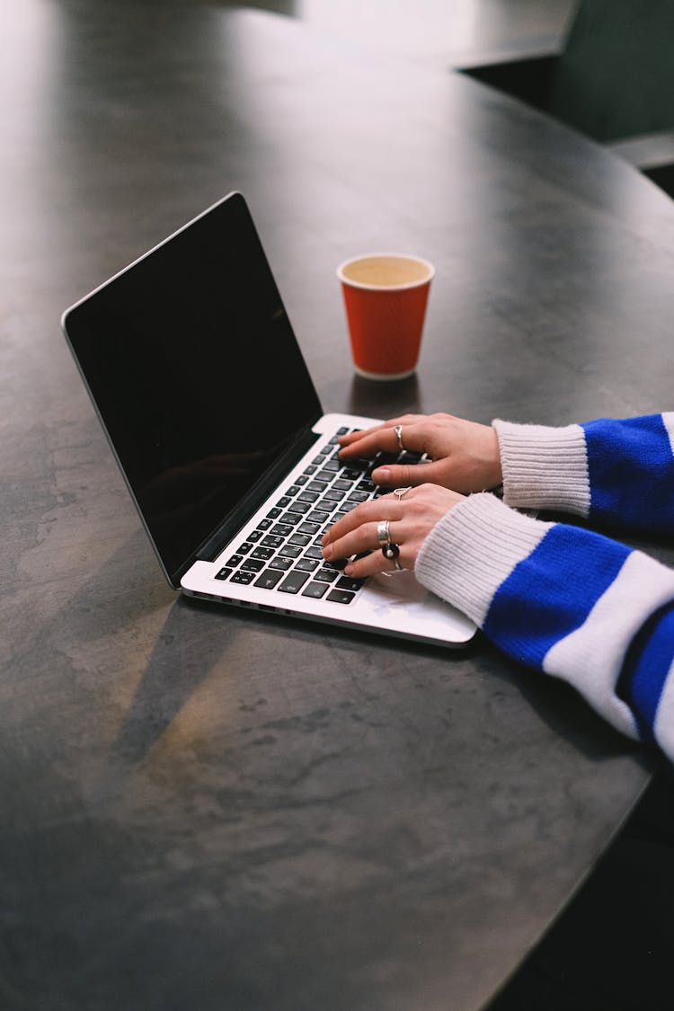 Hands Wearing Striped Sweater Working On Laptop