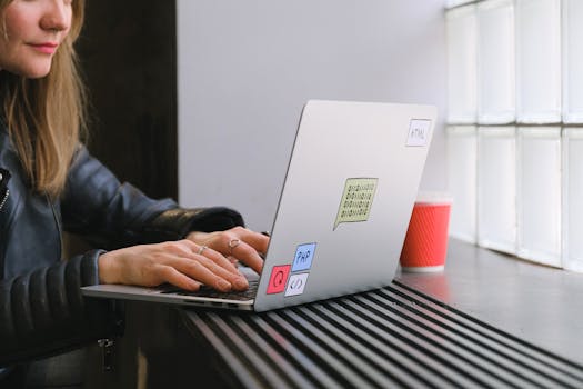 Woman using a laptop by a window in a cafe with a coffee. Ideal for tech and lifestyle themes.