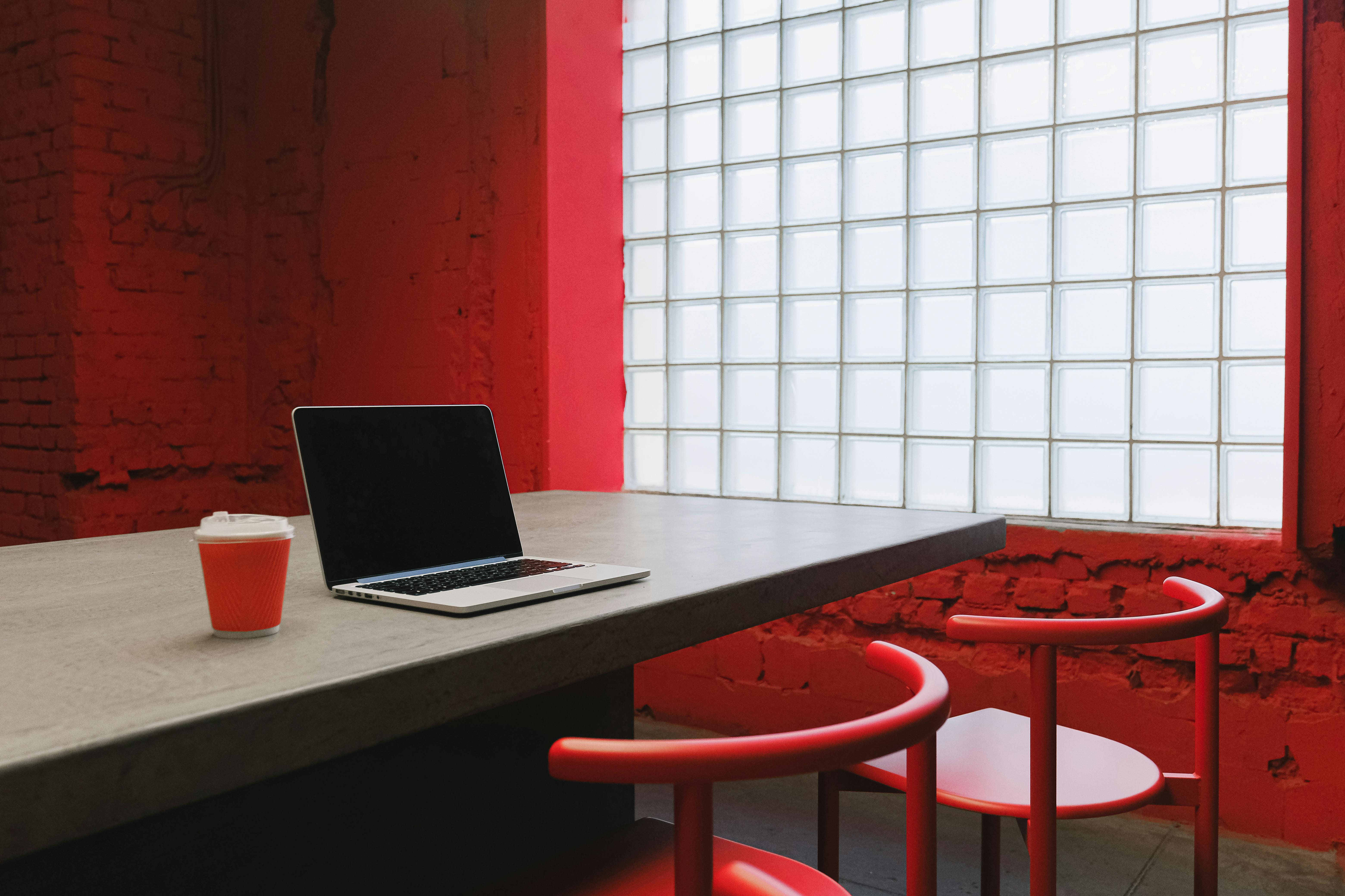 red chairs by wooden table with laptop on top