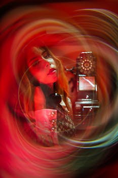 Creative photo with blurred motion and vintage telephone booth, featuring a model in vibrant warm tones.
