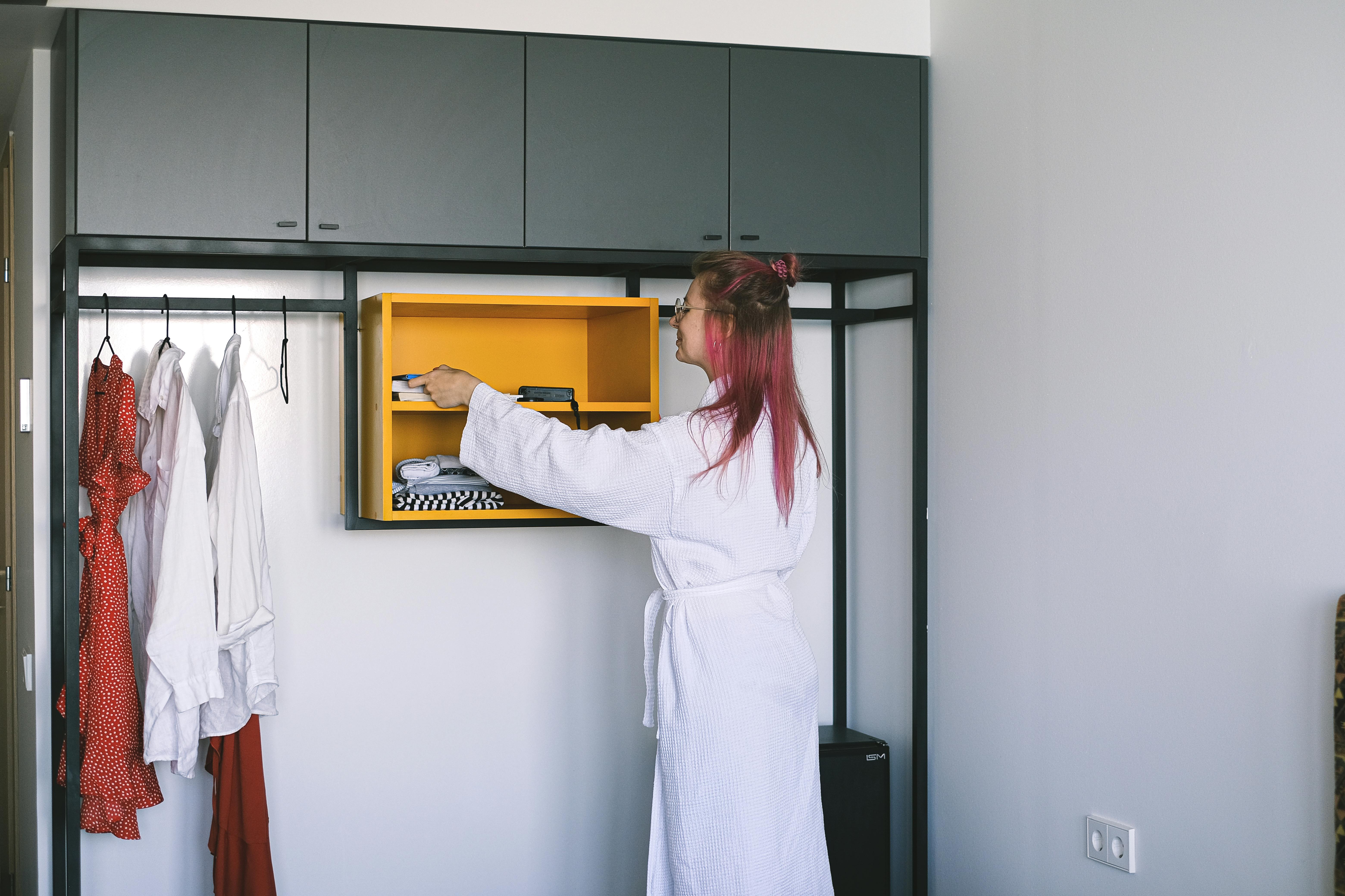 woman in bathrobe standing by shelves