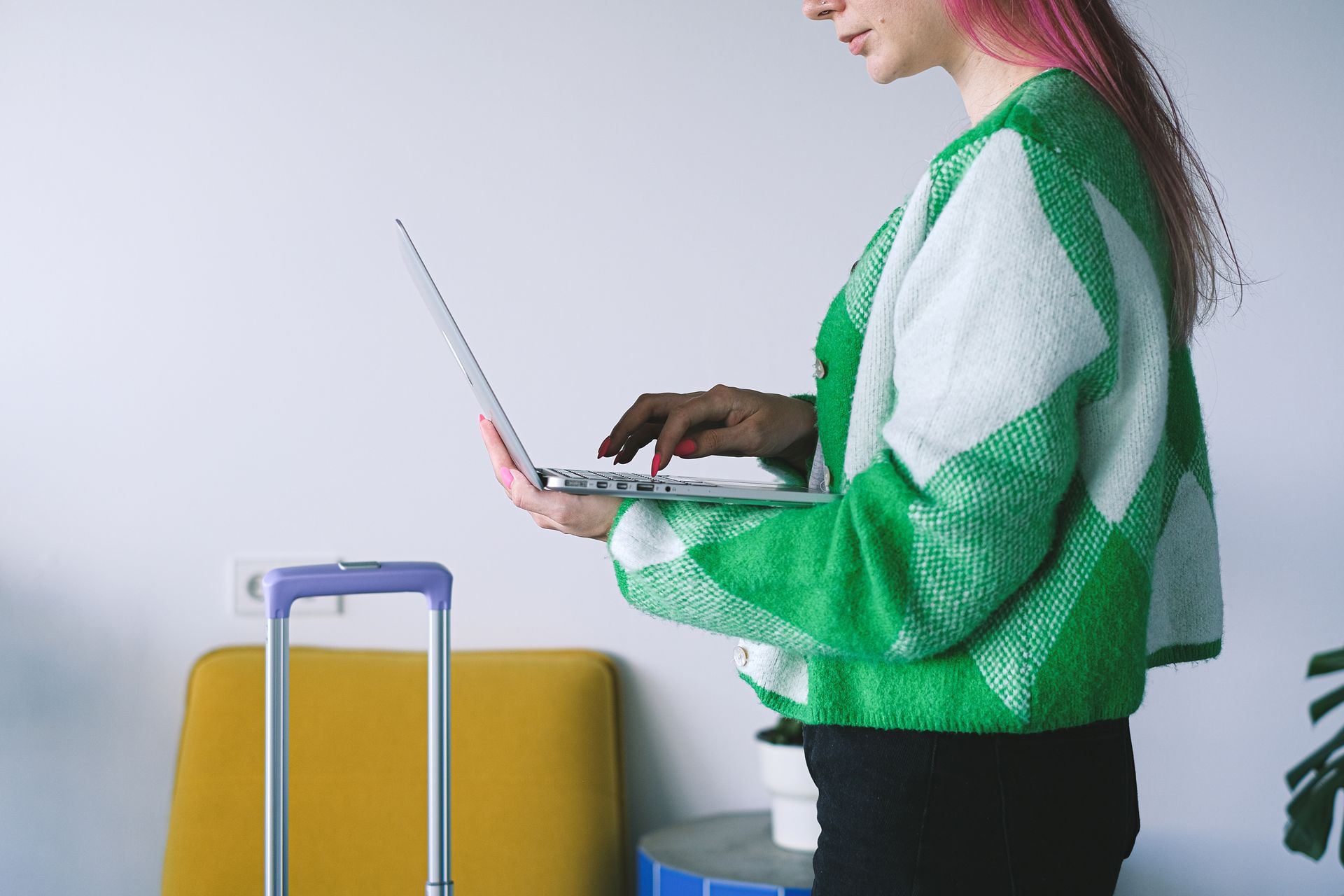 Young woman working on laptop near luggage in stylish hotel lounge, embracing the digital nomad lifestyle.