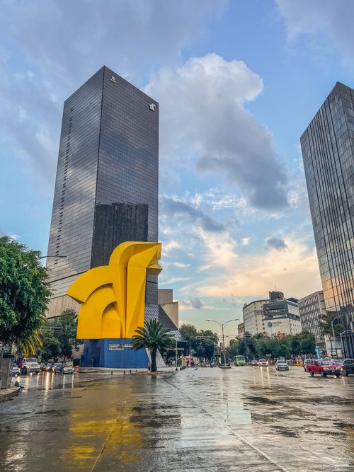 Free View of skyscrapers and the iconic Caballito monument along a wet roadway in Mexico City. Stock Photo