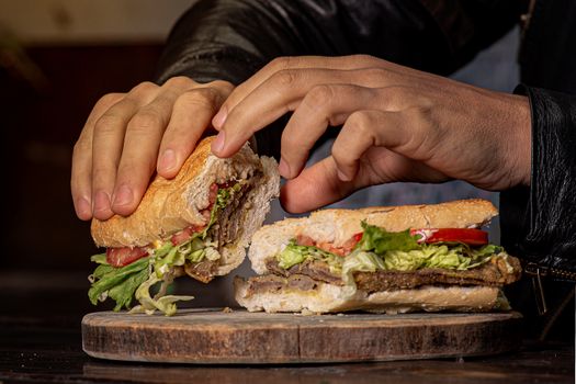 Close-up of a tasty ham sandwich with fresh lettuce and tomato on a wooden board.