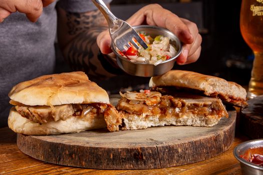 Tasty sandwich with pickled vegetables served on a rustic wooden platter.