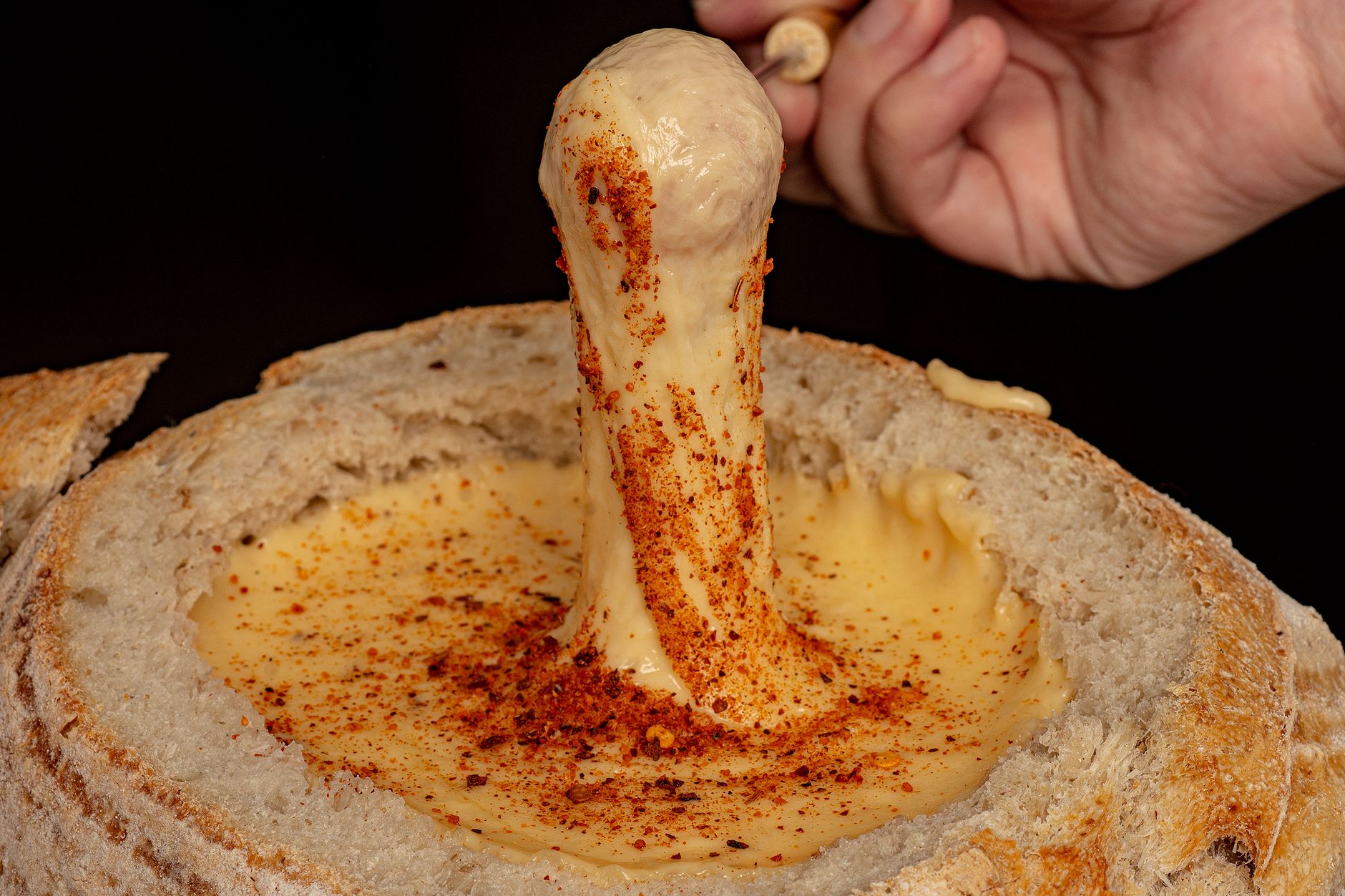 Creamy beer cheese sauce poured into bread bowl