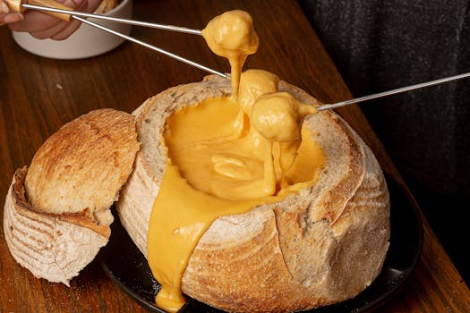 Scrumptious cheese fondue in a rustic bread bowl on a wooden table.