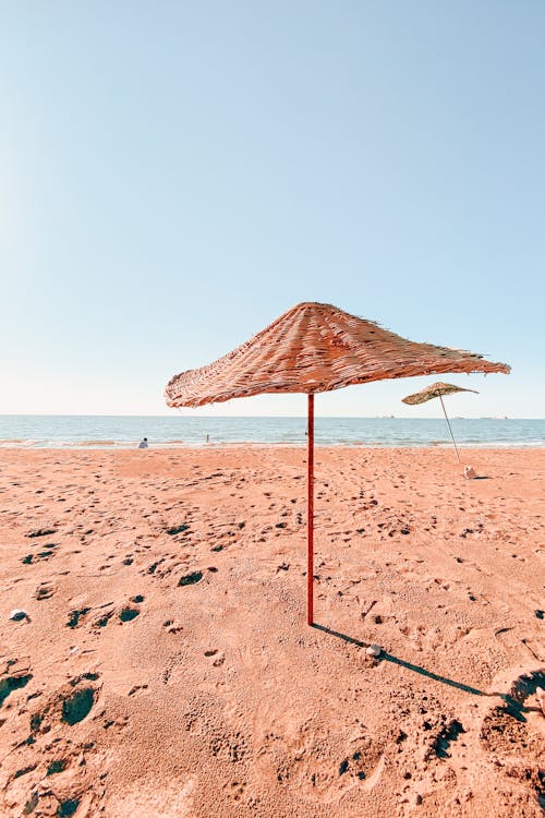 Free Rattan Umbrella in Beach Sand Stock Photo