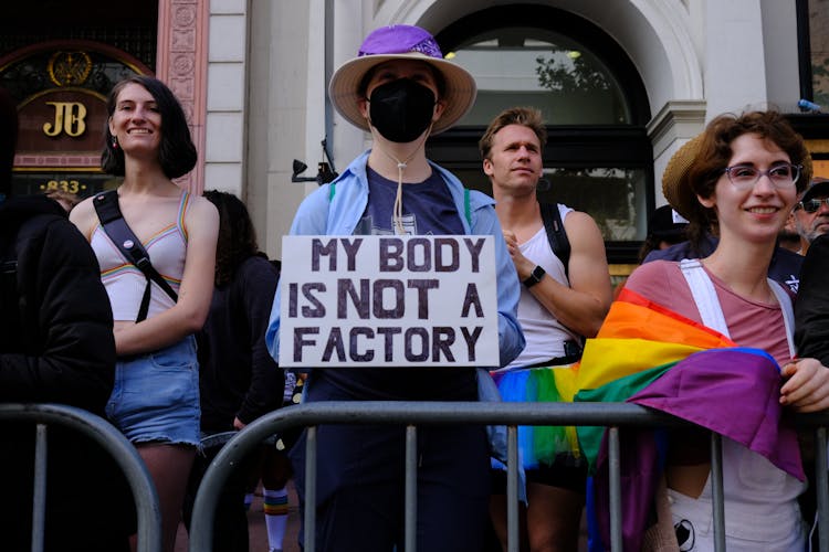 Person Wearing Face Mask Holding Sign At Protest