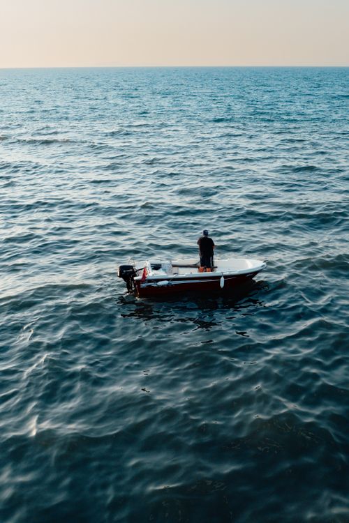 Free A lone fisherman on a small boat in the tranquil ocean waters of Yalova, Turkey. Stock Photo