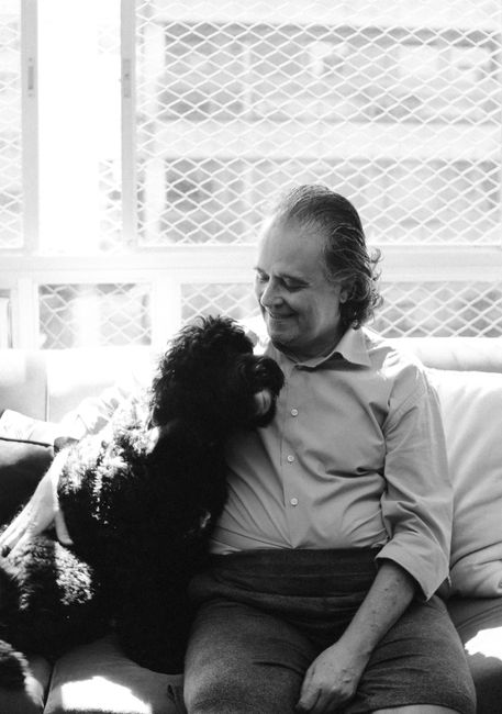 Elderly man and happy dog bonding on a sunny day indoors.