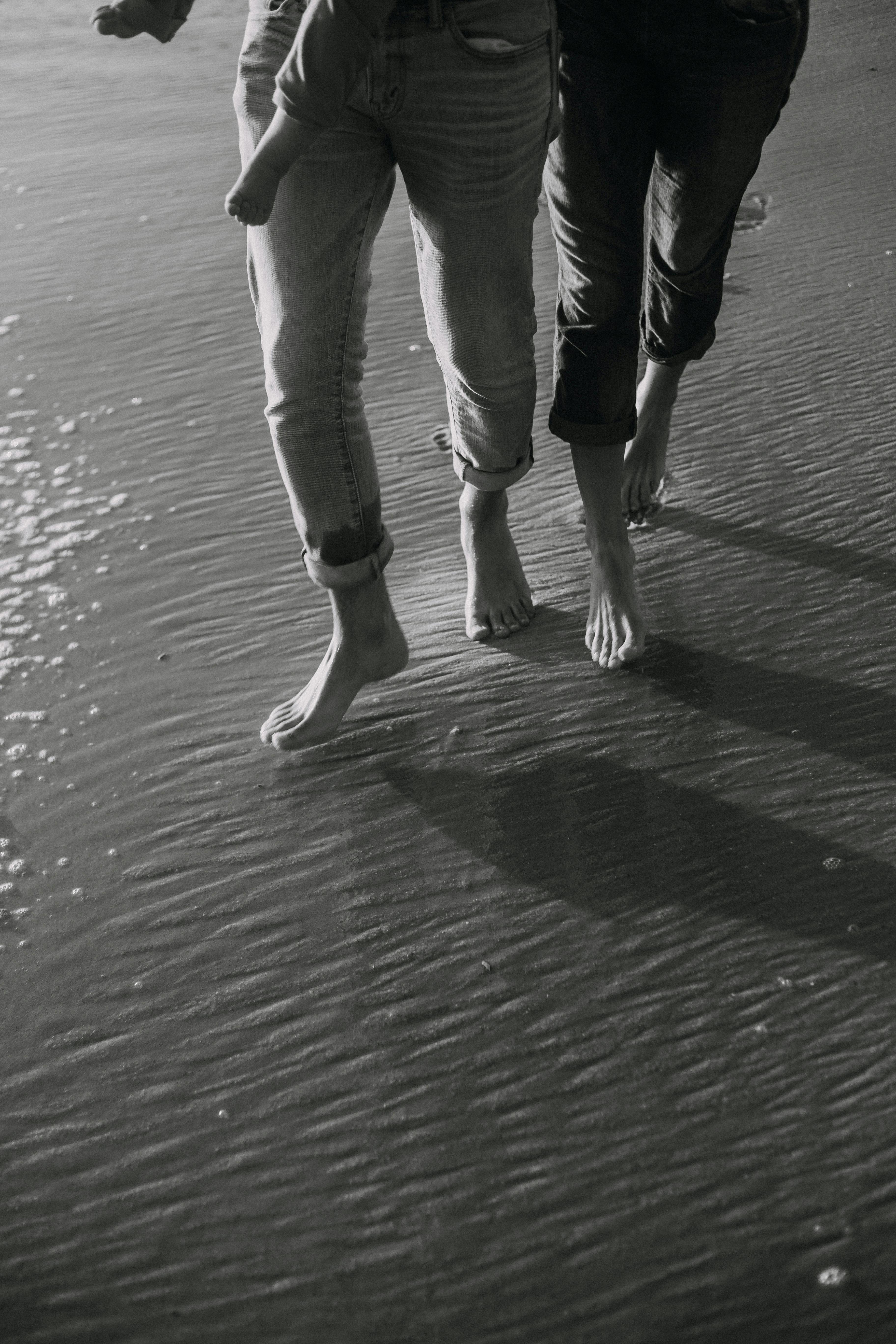 bare feet of people walking on a beach