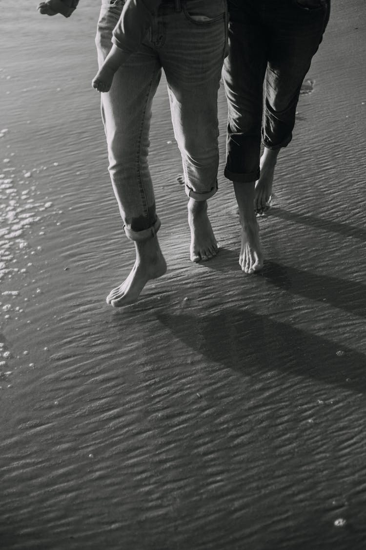 Bare Feet Of People Walking On A Beach