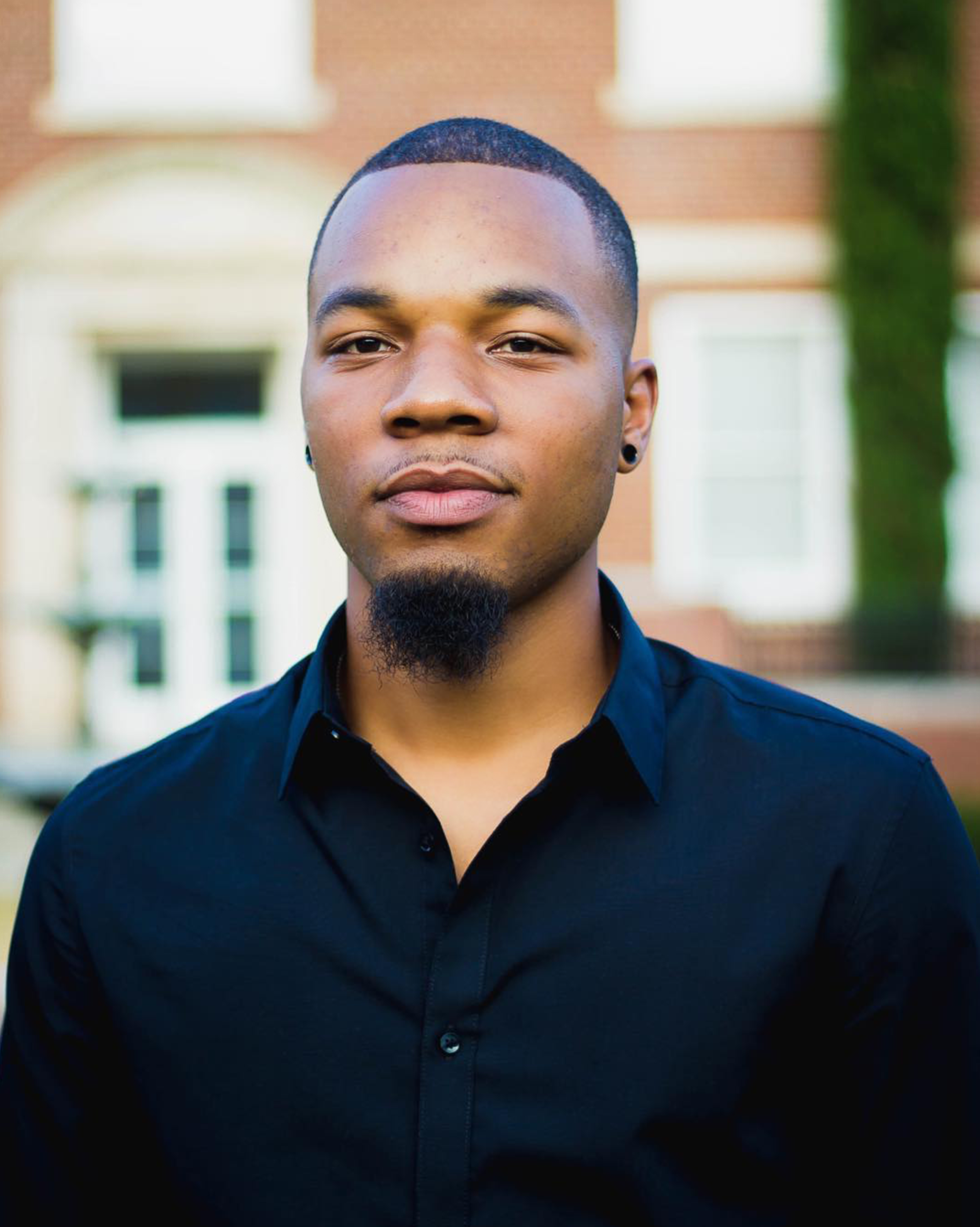 A confident African American man with facial hair smiling outdoors in Atlanta, GA.