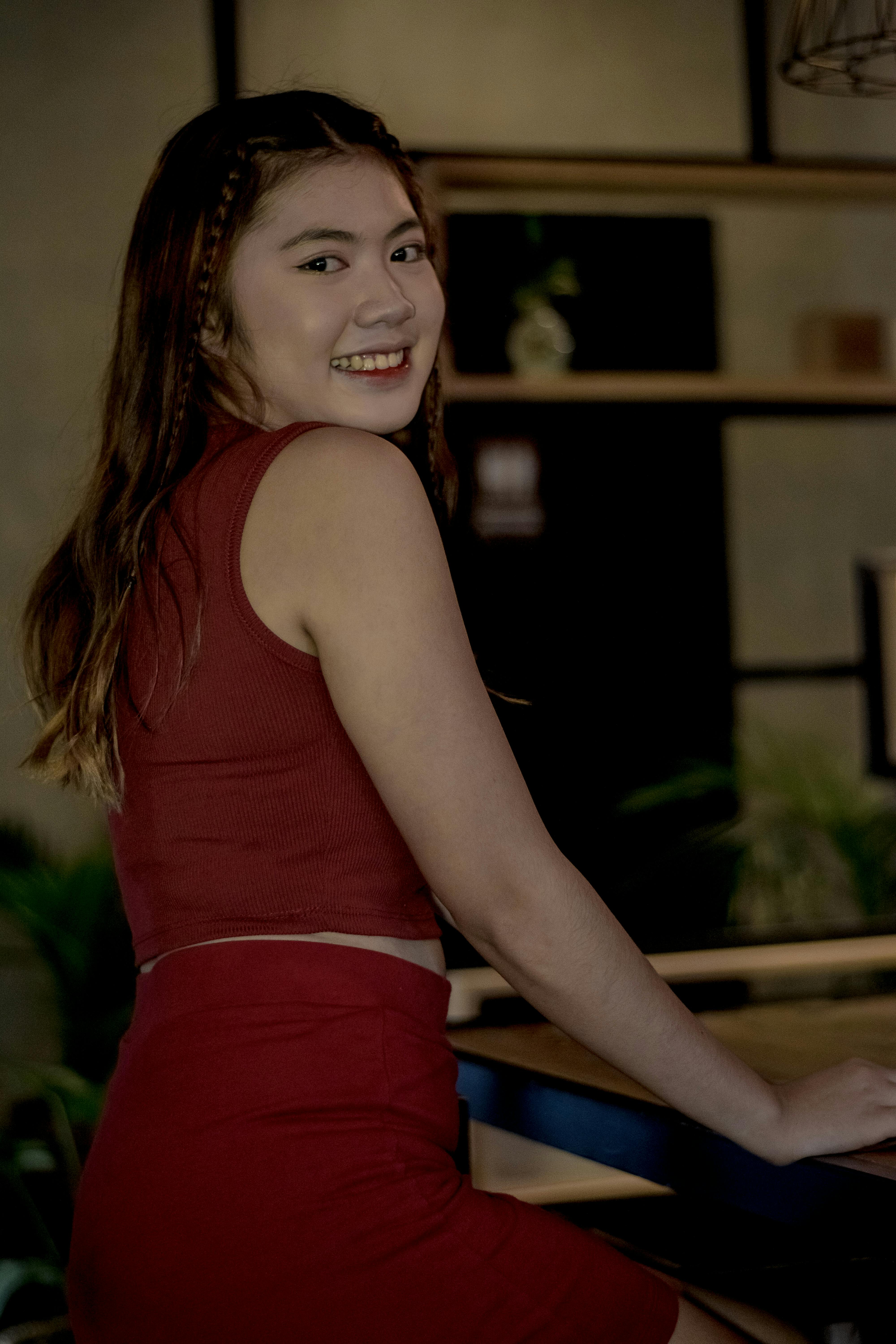 A Beautiful Woman in Brown Tank Top Smiling while Looking Over Shoulder