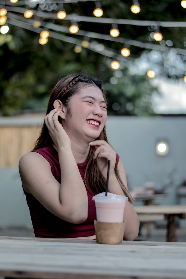 Laughing Woman Sitting By Table In Cafe