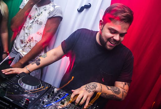 Energetic DJ with tattoos mixes music at a lively nightclub party.