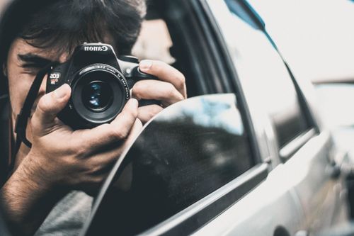 Free A photographer taking a picture from a car window with a DSLR camera. Stock Photo