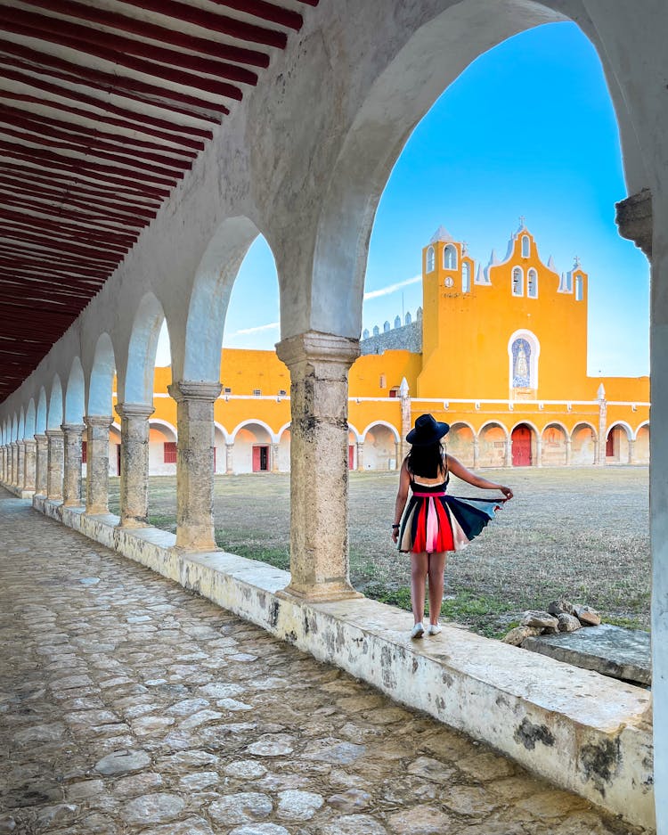 Photo Of A Woman In A Colorful Dress Against The Background Of The Convent Of San Antonio, Izamal, Mexico