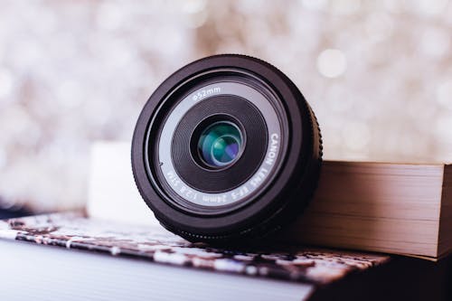 Black Canon Zoom Lens Leaning on Book