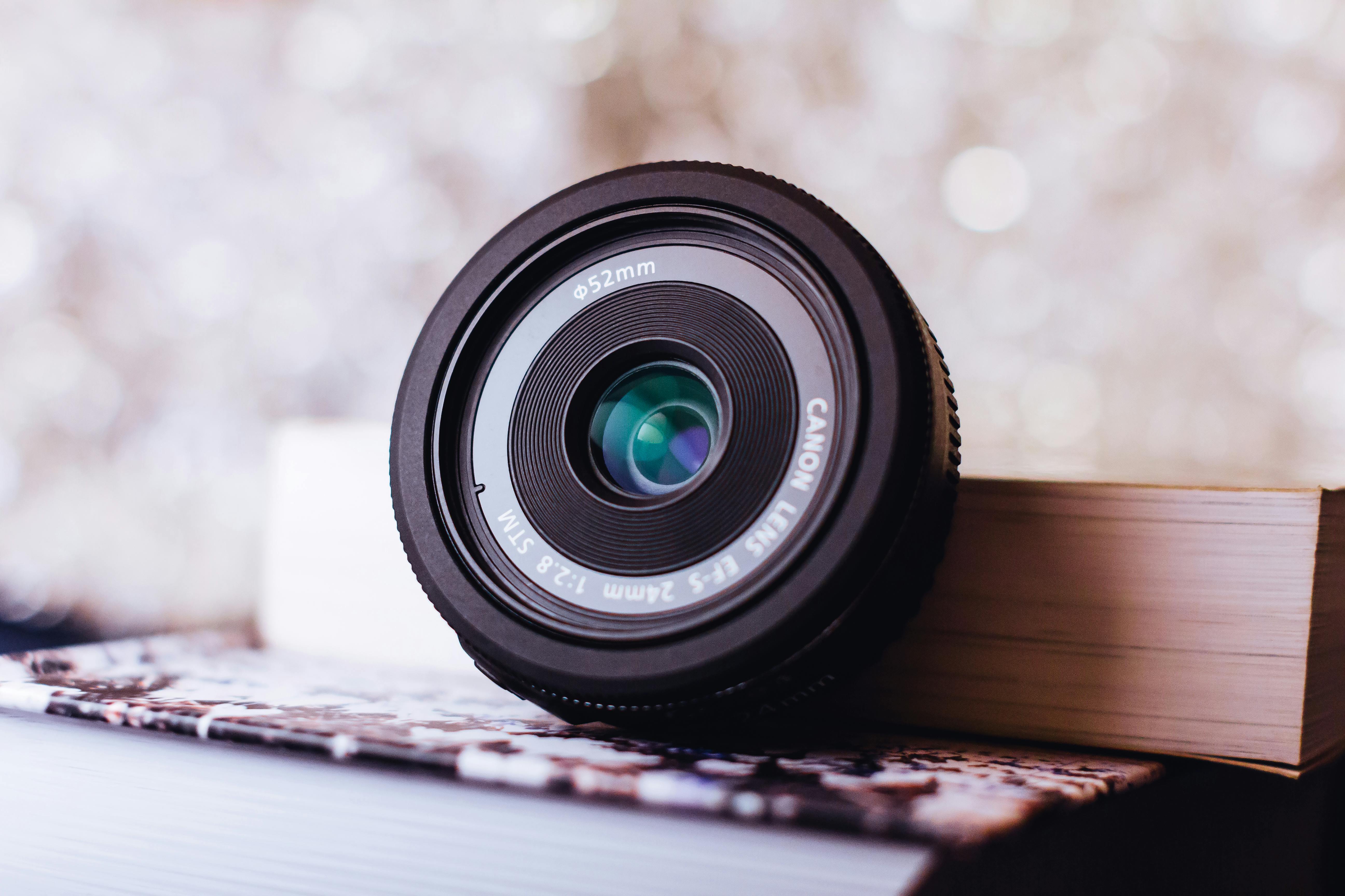 Black Canon Zoom Lens Leaning on Book · Free Stock Photo