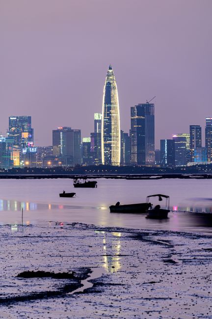 A striking cityscape with illuminated buildings reflecting on the water at twilight.