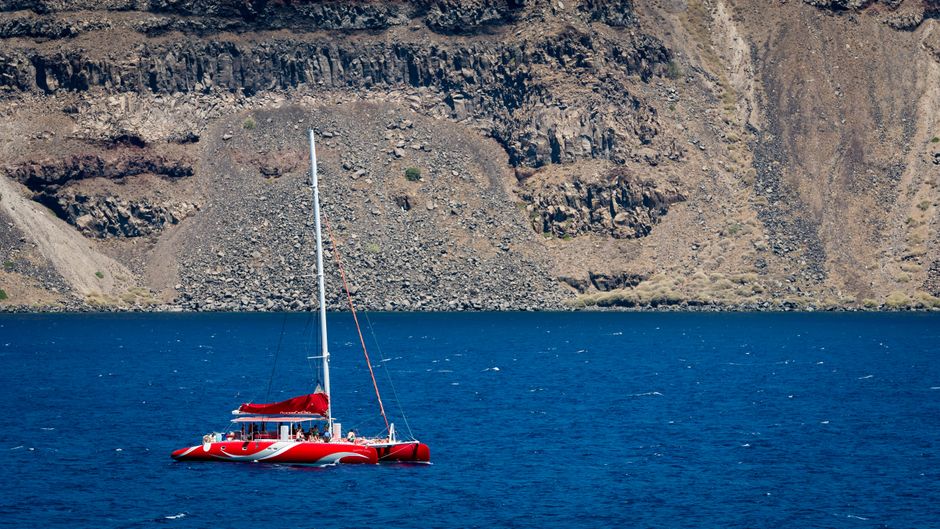 Catamaran cruise near Red Beach in Santorini, Greece, with clear blue waters