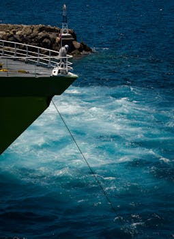 一名男子站在甲板上，俯瞰着波涛汹涌的蓝色海洋