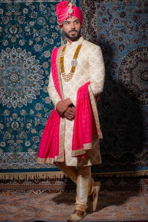 Free Model in traditional Indian wedding attire posing against decorative carpets. Stock Photo