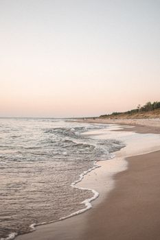 Serene sunset view of Palanga beach with gentle waves and soft sand shoreline.