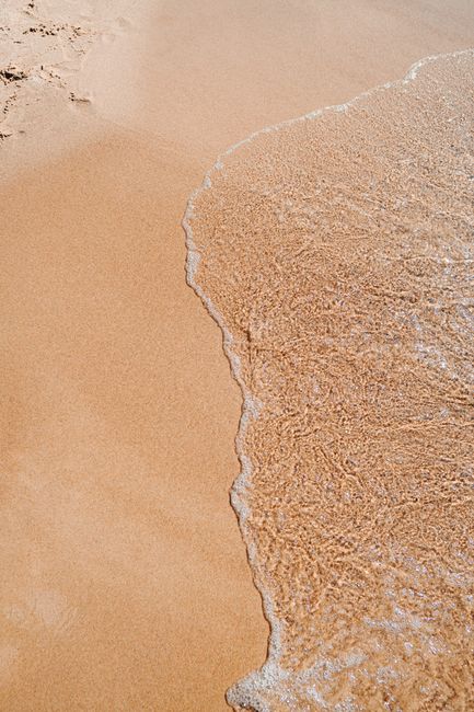 Gentle waves meet sandy shore at Palanga beach, Lithuania, on a sunny day.