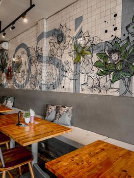 Inviting café setting with a stunning floral mural and cozy wooden furniture.