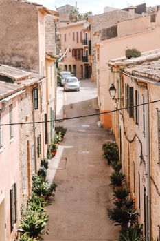 Explore a picturesque alleyway in an old Spanish town with rustic facades and vibrant plants.