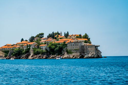 Free Charming coastal town with orange roofs and blue sea in Montenegro, offering scenic tranquility. Stock Photo