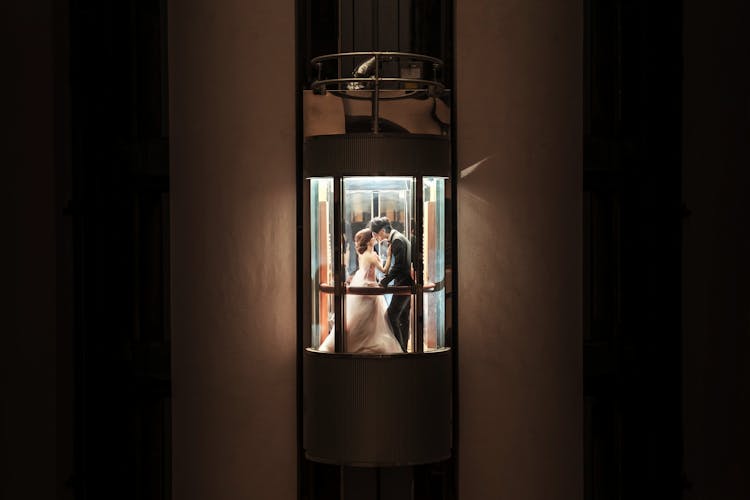 Atmospheric Image Of Newlyweds Kissing In An Elevator