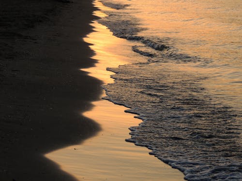 Sea Waves Crashing on Shore During Sunset