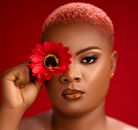 Elegant close-up portrait of a woman holding a red flower against a vibrant red background.