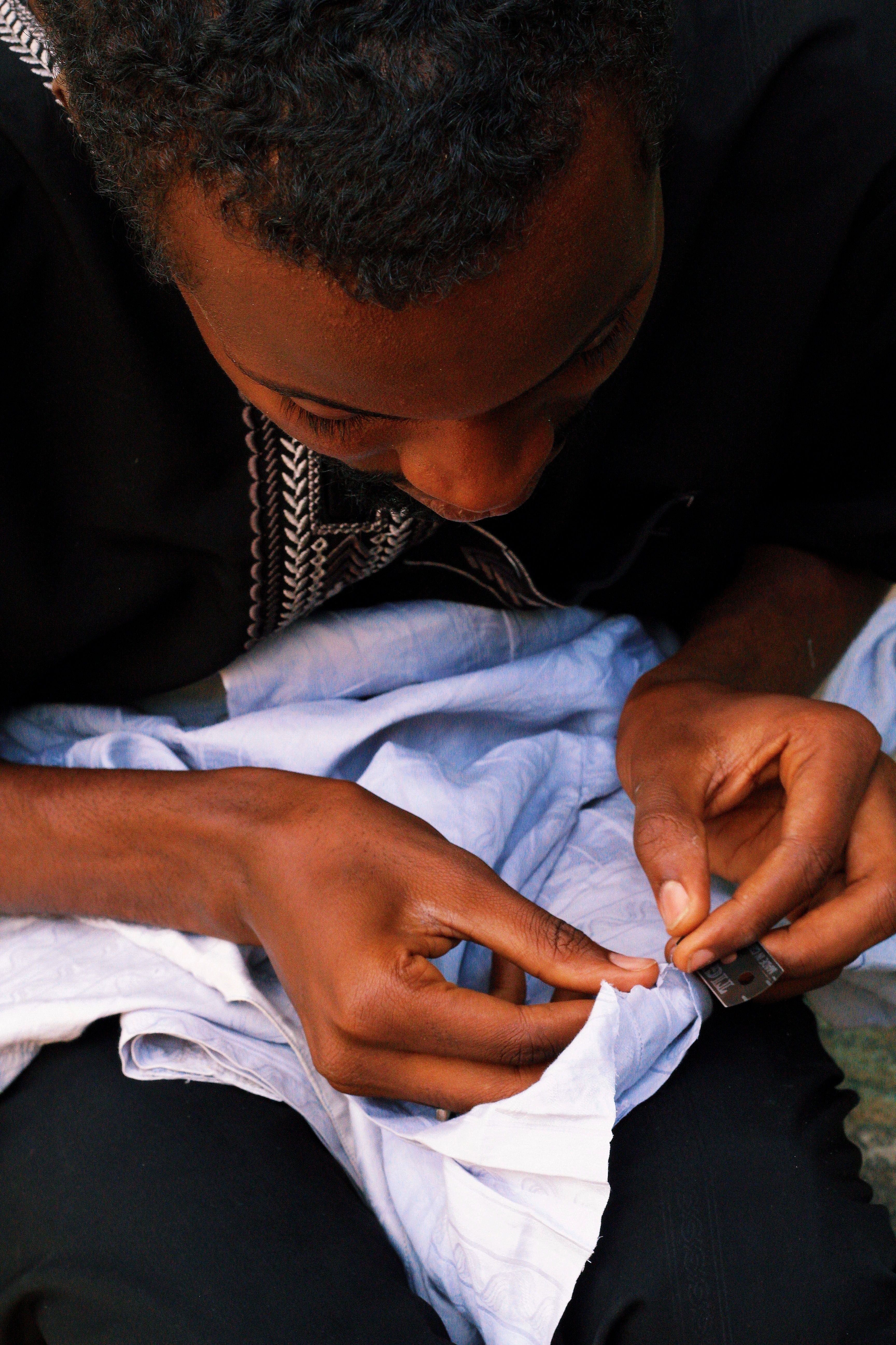 Detailed view of a person focusing on sewing a piece of fabric by hand.