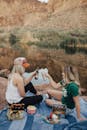 两个女人在风景如画的湖边野餐，喝酒吃零食