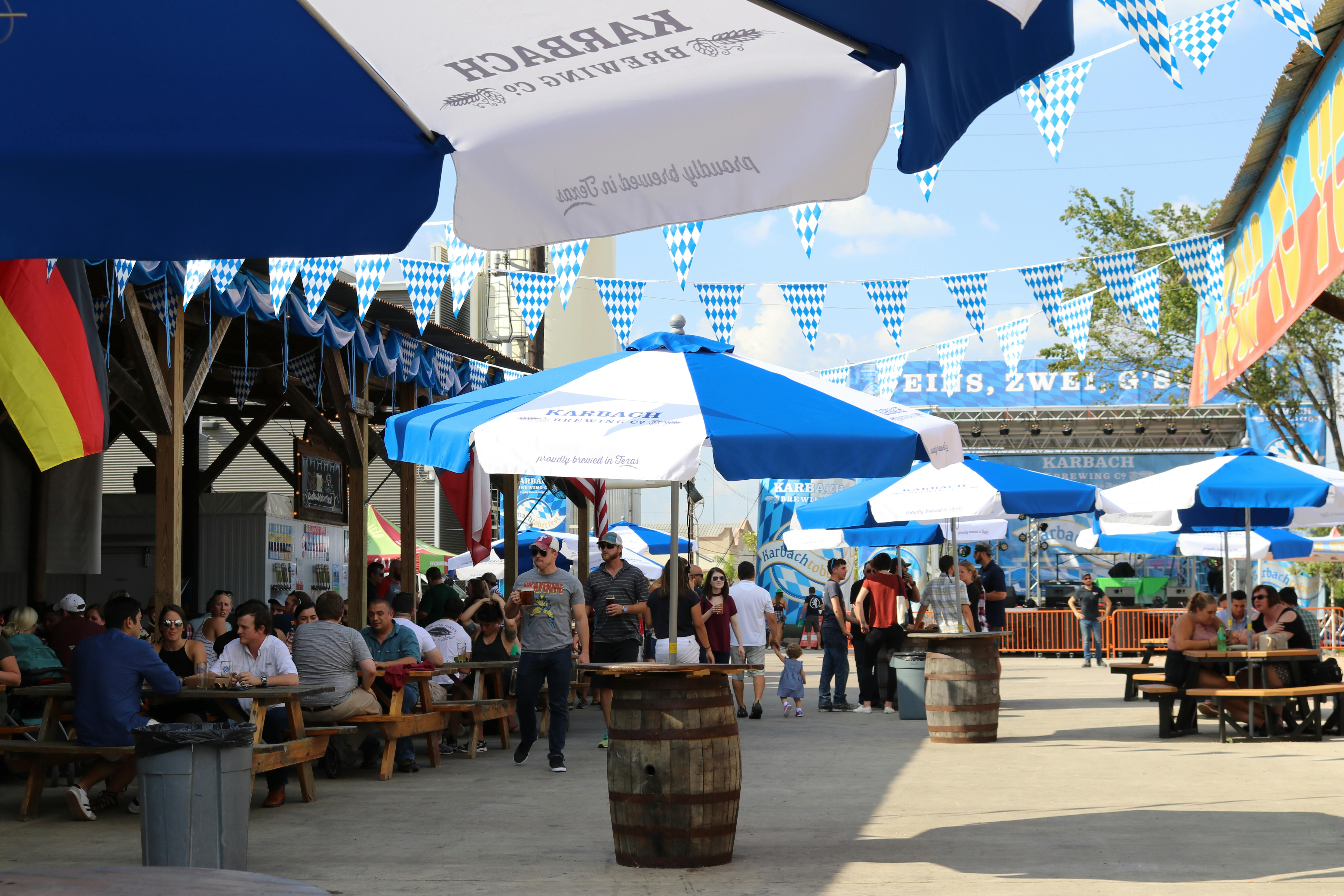 节日里热闹非凡，人们撑着色彩缤纷的雨伞享用食物和饮料，户外彩旗飘扬