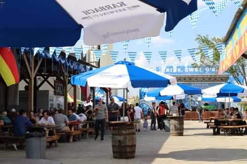 Free Lively festival with people enjoying food and drinks under colorful umbrellas and bunting outdoors. Stock Photo