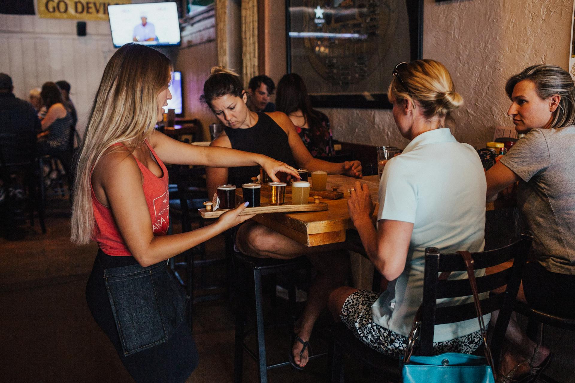 Woman Serving Drinks on Women Sitting Inside an Establishment