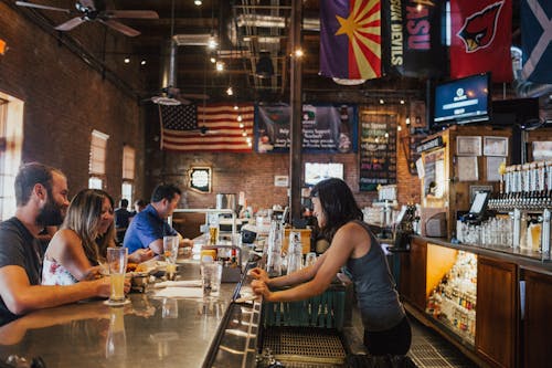 Free Woman Wearing Gray Tank Top in Bar Counter Attending Costumers Stock Photo